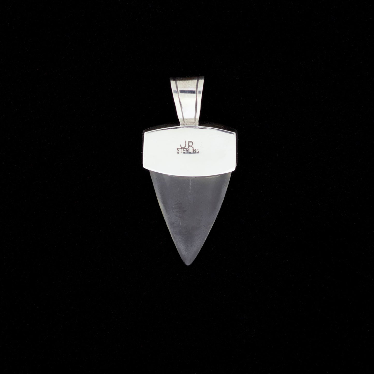 Fossil mako shark tooth pendant with silver on a black background.