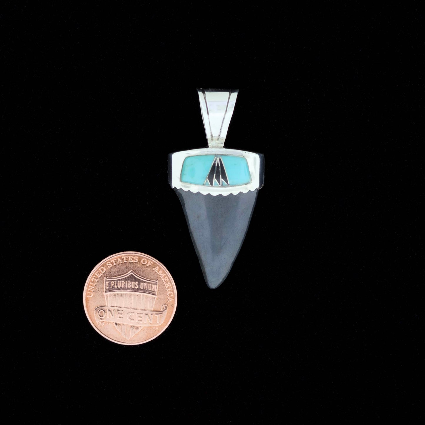 Fossil mako shark tooth pendant with blue turquoise and black onyx inlay on a black background