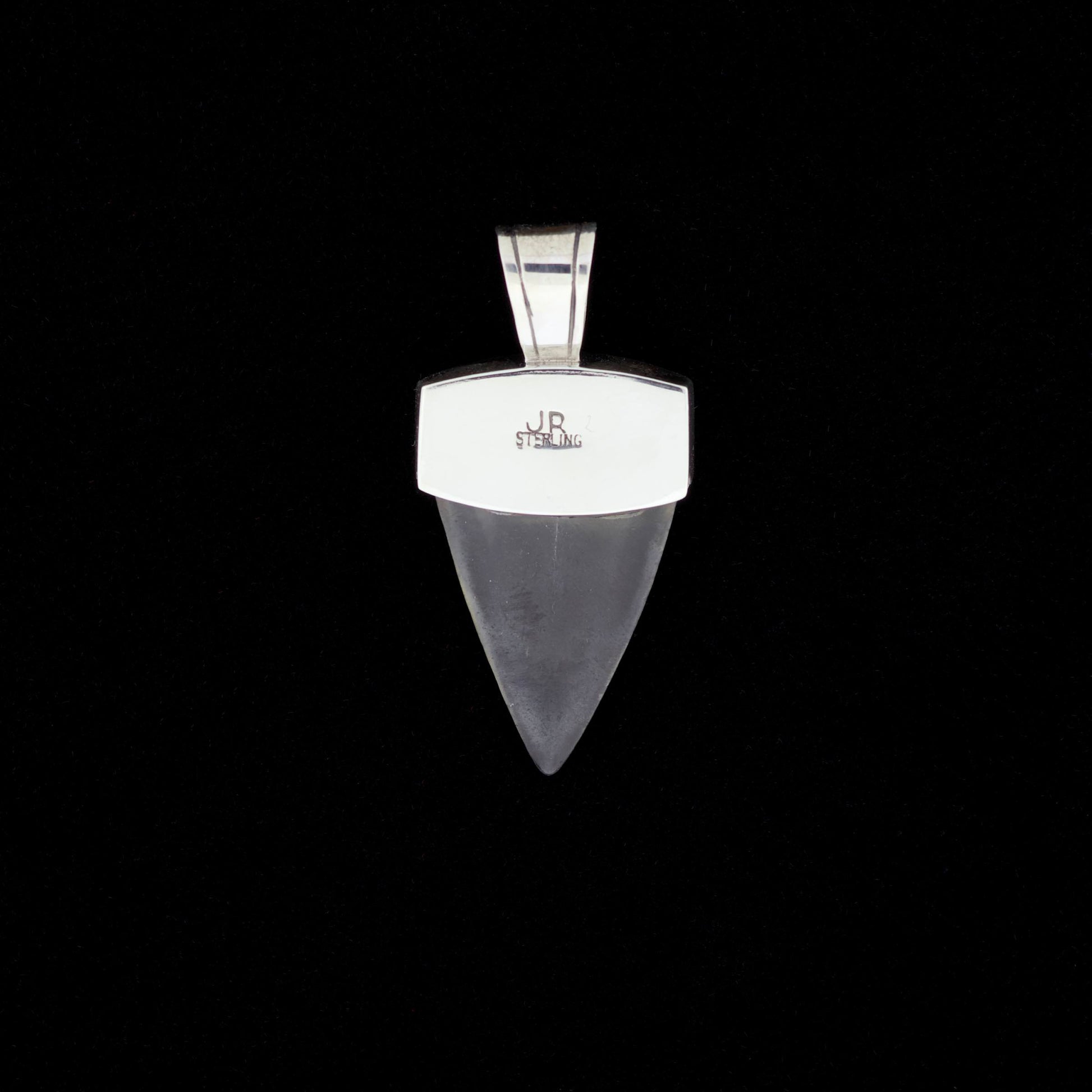 Fossil mako shark tooth pendant with silver on a black background.
